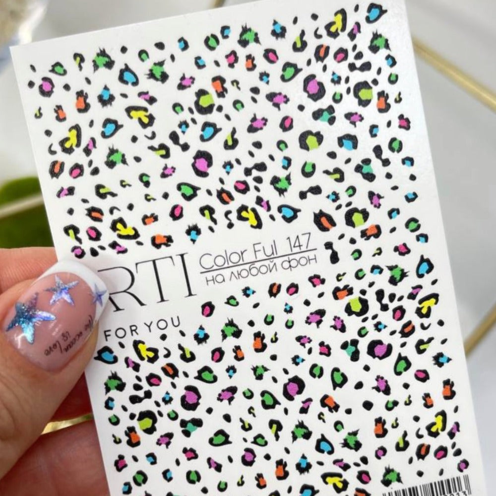 Colorful leopard print nail art stickers held by a hand with star design manicure