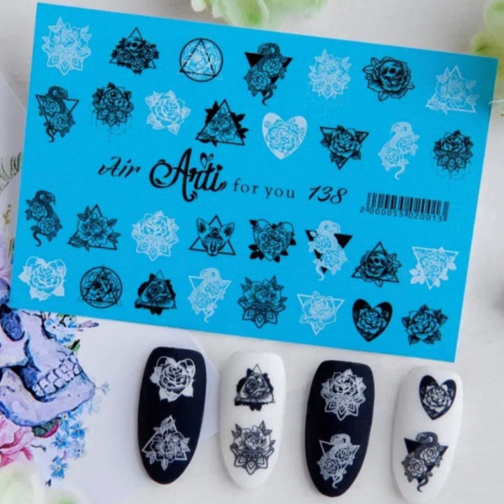 Sheet of black and white floral nail art stickers with sample designs on artificial nails