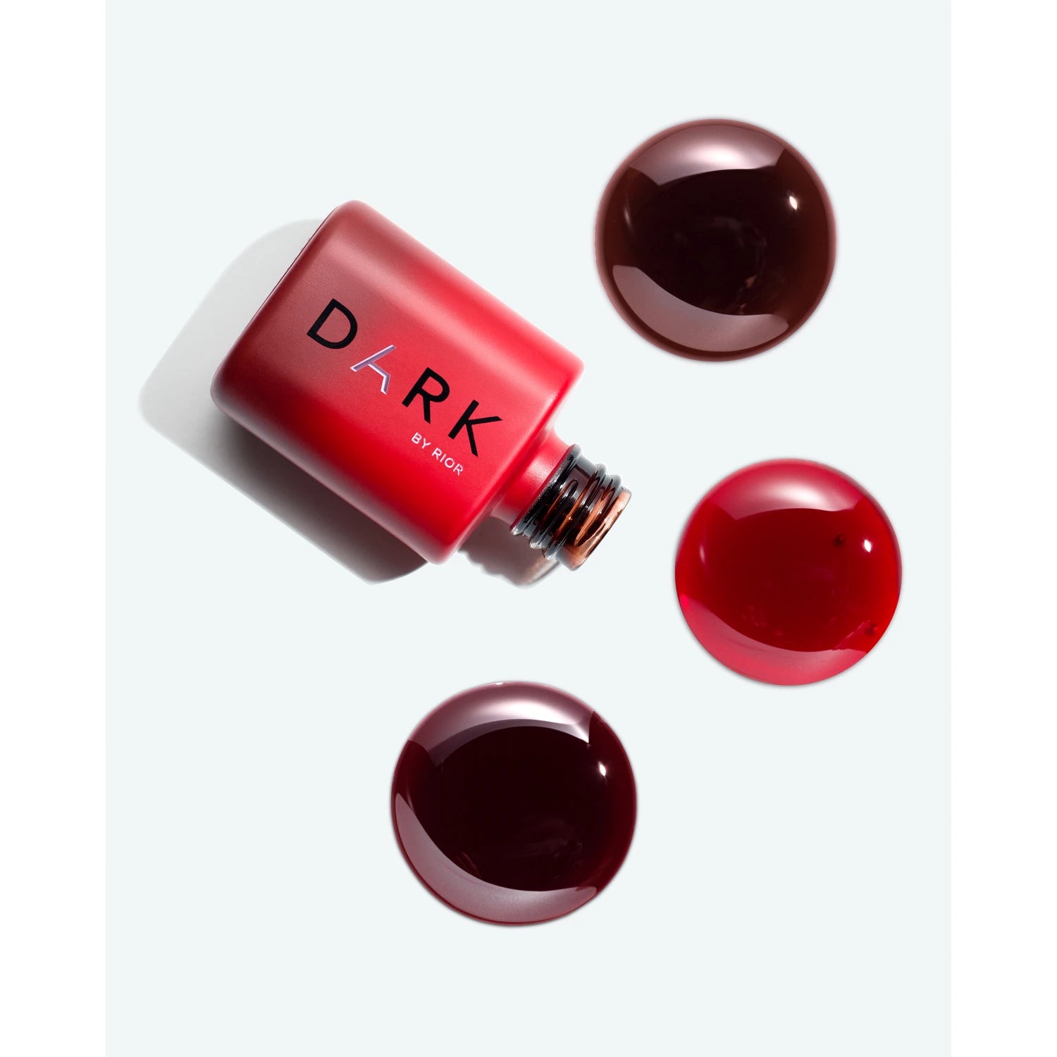 Red gel nail polish bottle with dark red polish drops for manicure and pedicure