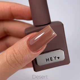 Hand holding brown gel nail polish bottle, painted nail in glossy nude brown shade