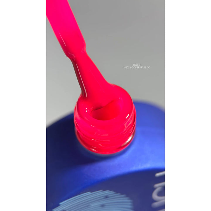 Neon pink nail gel polish brush above open blue bottle, close-up for manicure product