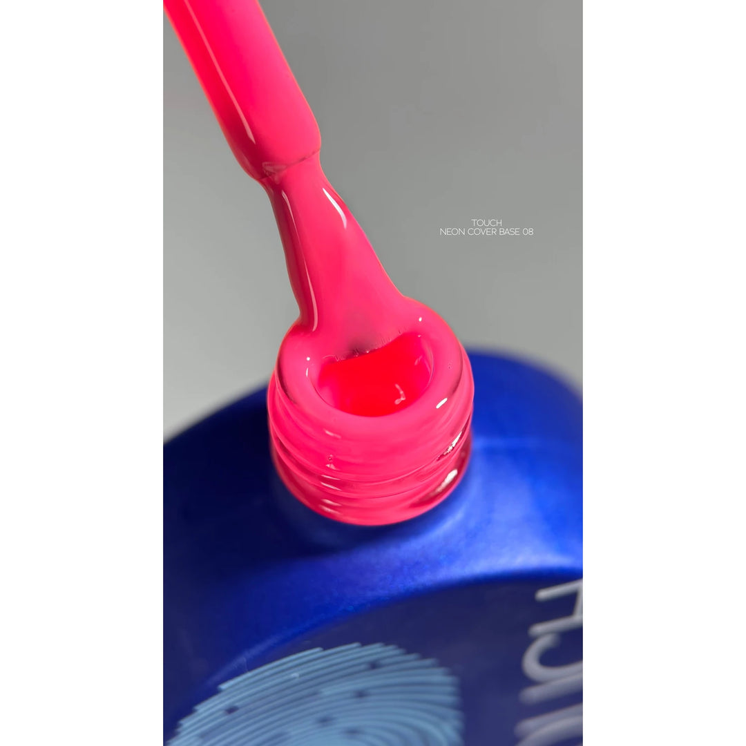 Neon pink UV gel nail polish being lifted from a blue bottle, close-up shot