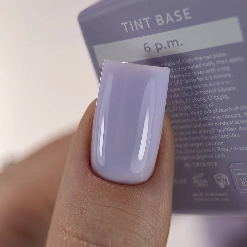 Close-up of a fingernail with glossy lavender UV gel polish, nail product label in background