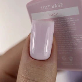 Close-up of a hand with glossy light pink gel nail polish, holding a 'Tint Base Lace' bottle.