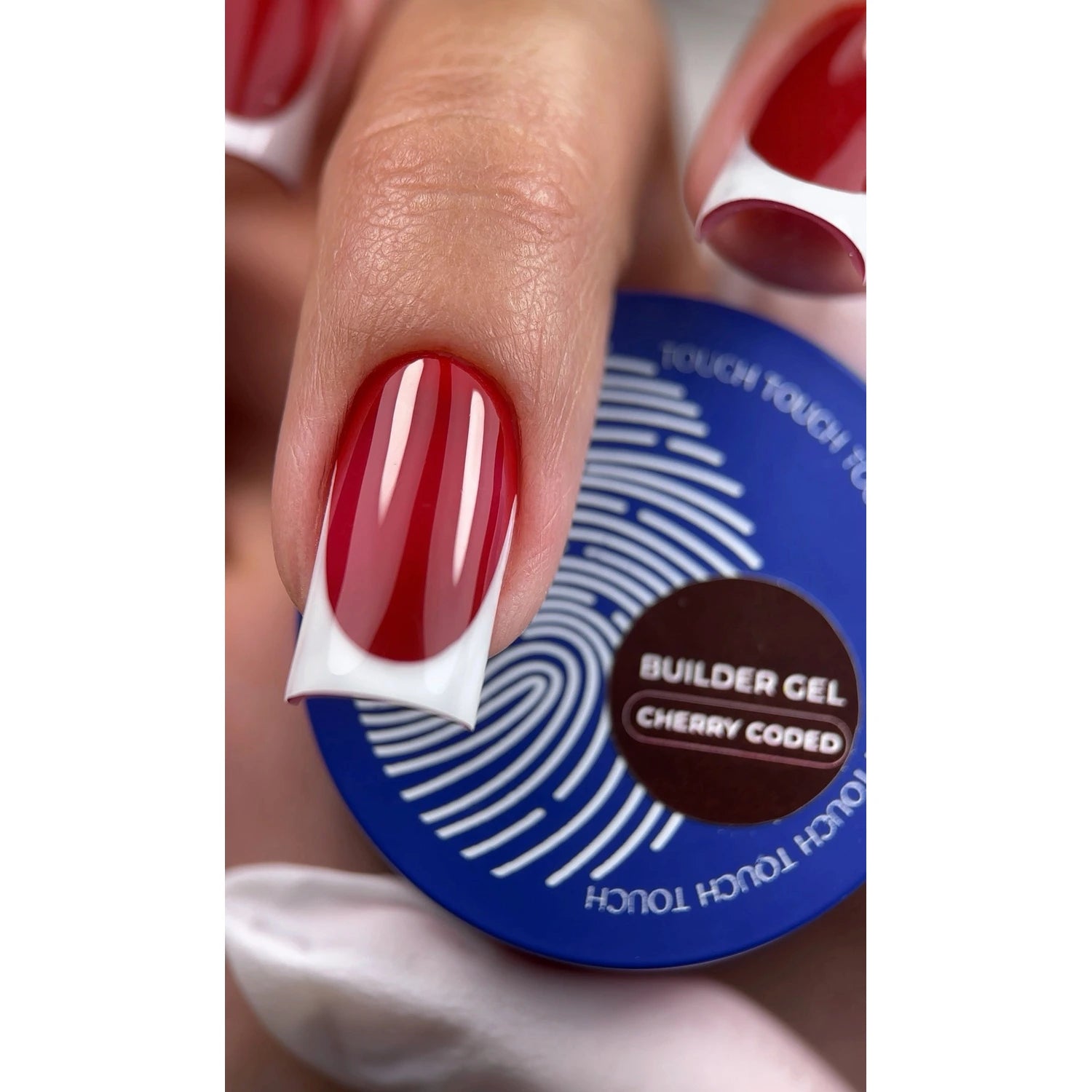 Hand with red and white French manicure holding Touch Builder Gel Cherry Coded jar