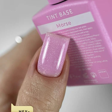 Close-up of a hand with pink glitter gel nail polish, holding a Morse tint base bottle.