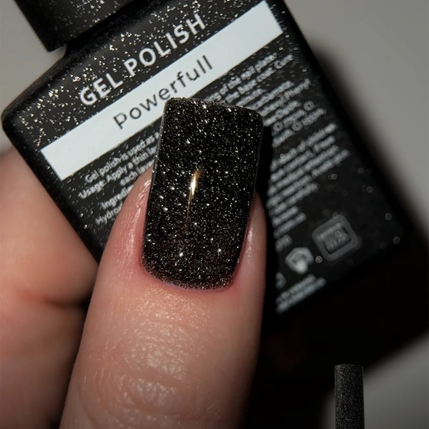 Black glitter gel nail polish on fingernail, close-up with polish bottle background