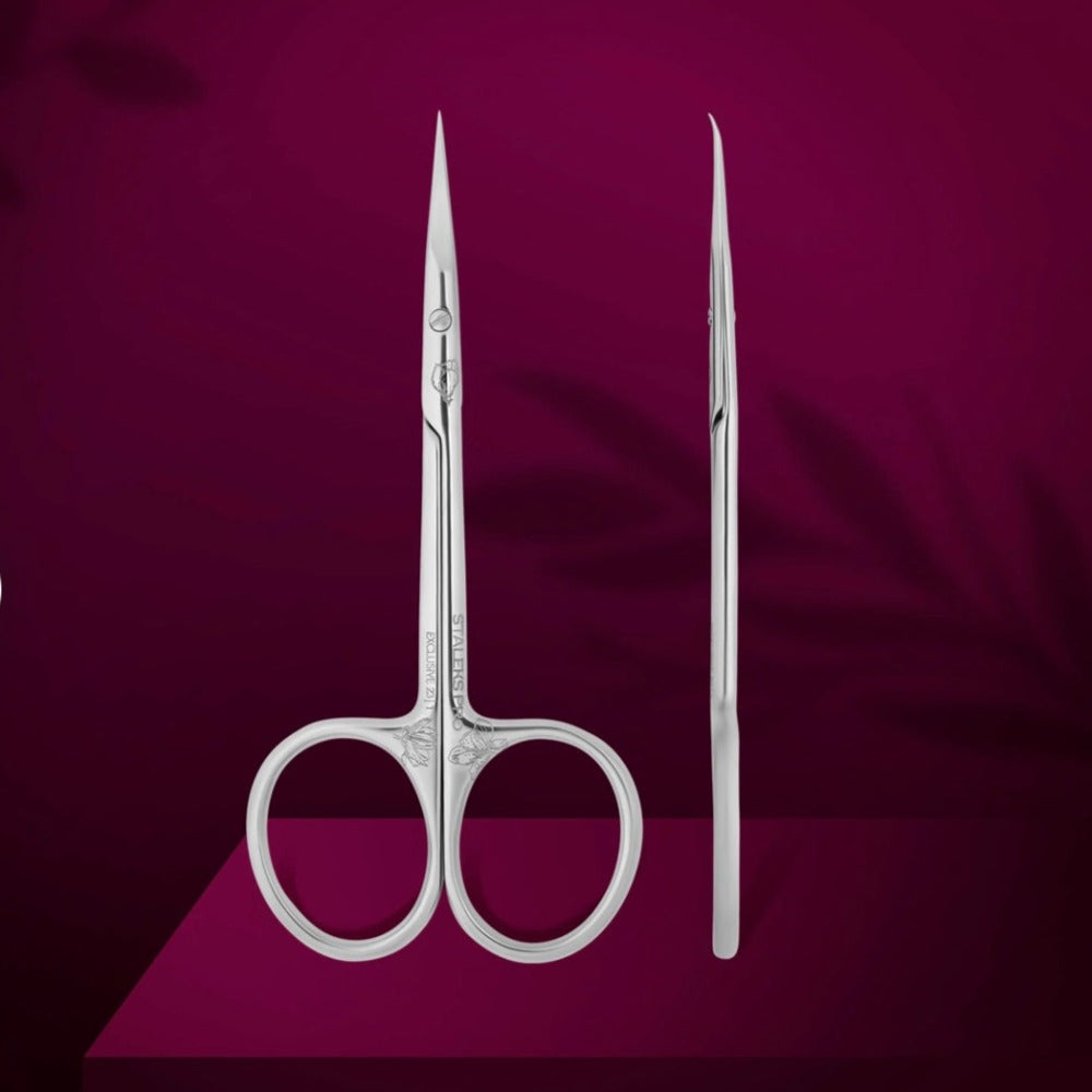 Stainless steel manicure scissors for nail care on a burgundy background
