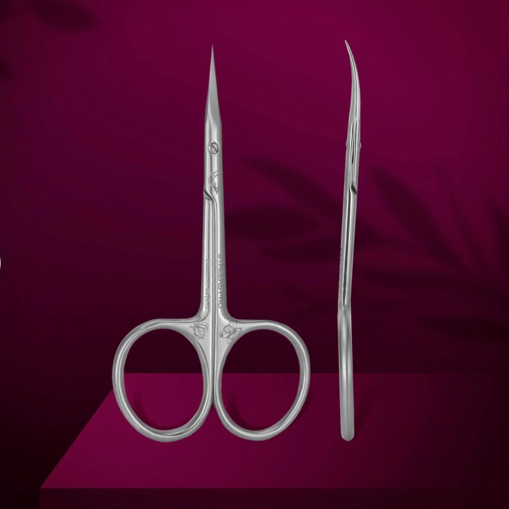 Professional stainless steel cuticle scissors for manicure and pedicure on a burgundy background