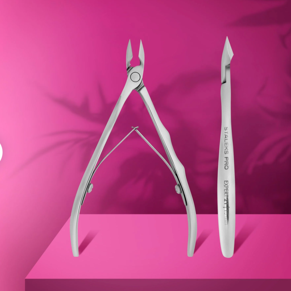 Professional stainless steel cuticle nipper and pusher for manicure on pink background