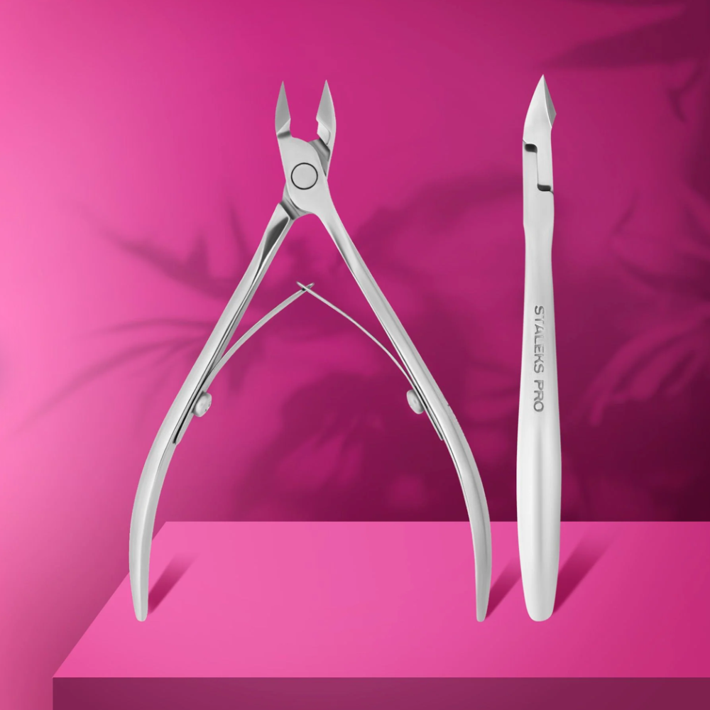 Stainless steel cuticle nippers and pusher for manicure on a pink background