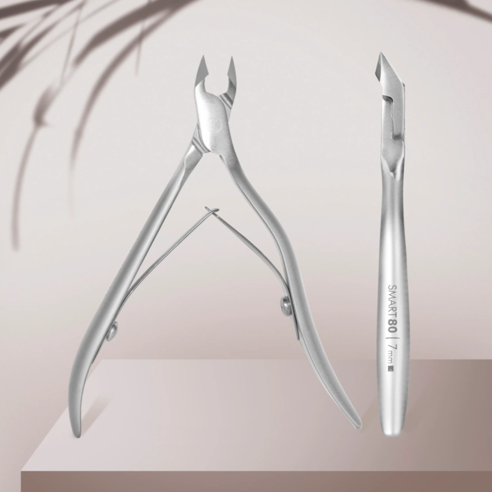 Stainless steel cuticle nippers and manicure tool on neutral background, professional nail care