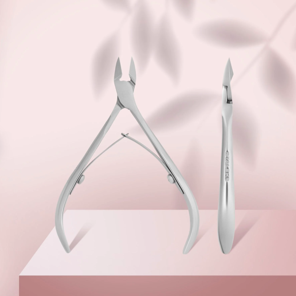Stainless steel cuticle nippers for manicure on a pink background with soft shadows