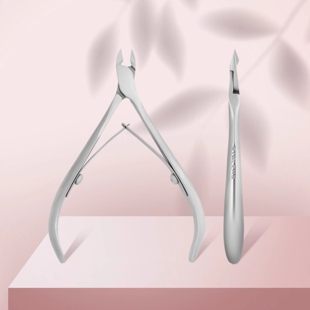Stainless steel cuticle nipper and manicure tool on a pink background, professional nail accessory
