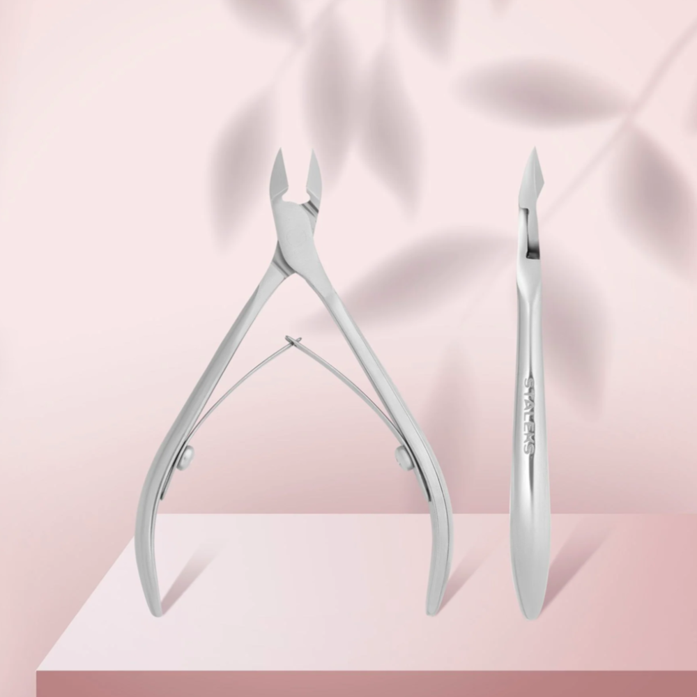 Stainless steel cuticle nipper for manicure on pink background with leaf shadow