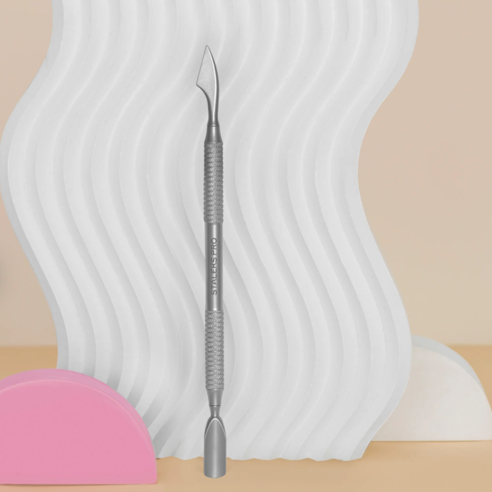 Stainless steel cuticle pusher for manicure and pedicure on abstract background