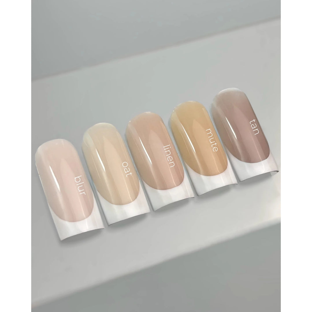 Neutral nude gel nail swatches labeled blur, oat, linen, mute, tan on display sticks