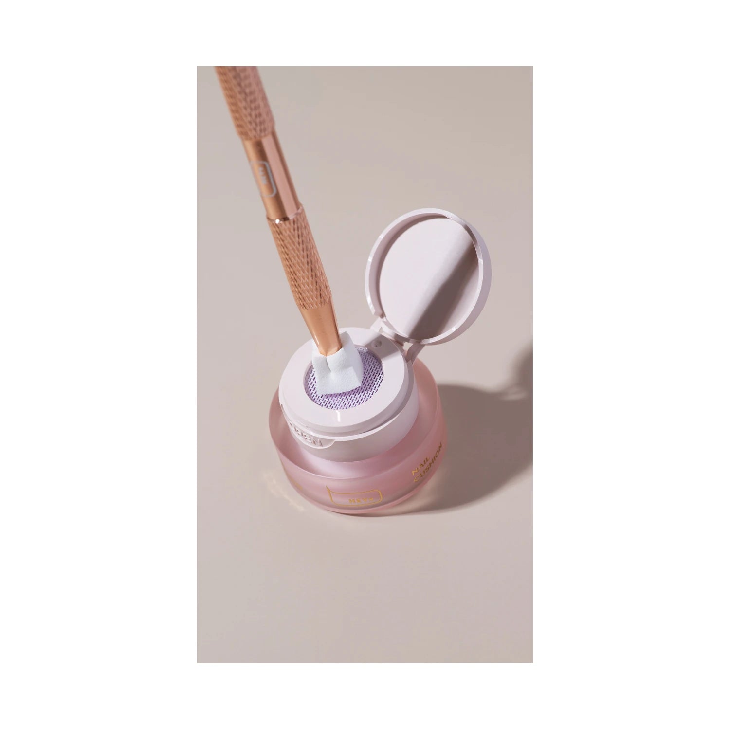Nail art brush cleaning tool with pink jar and gold handle, manicure accessory on neutral background