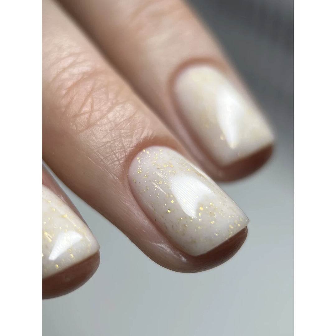 Close-up of nails with white gel polish and subtle gold glitter design