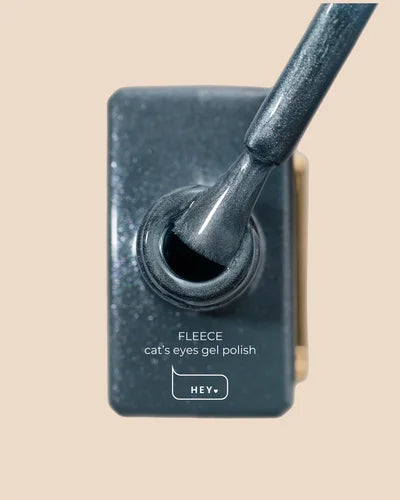 Cat's eyes gel polish with applicator on a beige background