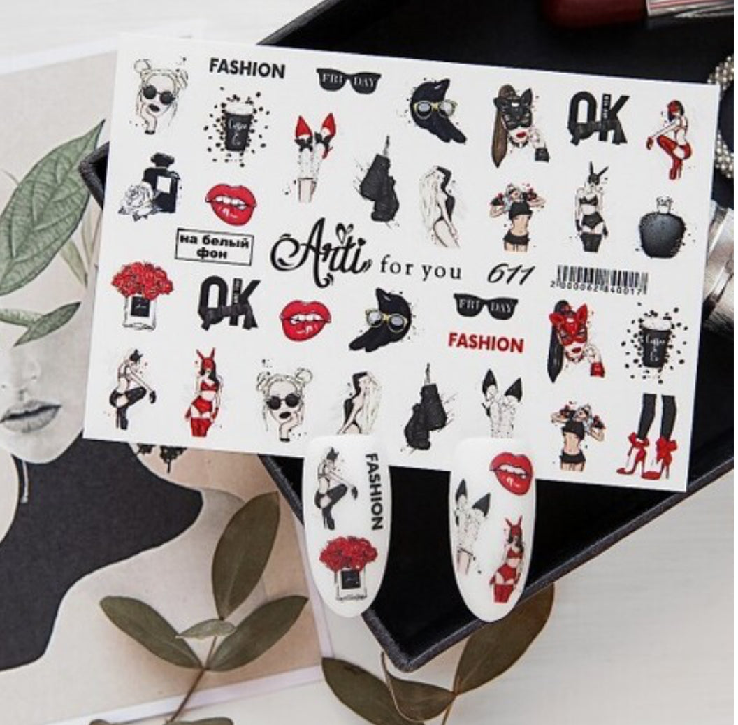 Sheet of fashion-themed nail art stickers with lips, makeup, and female illustrations on a table.