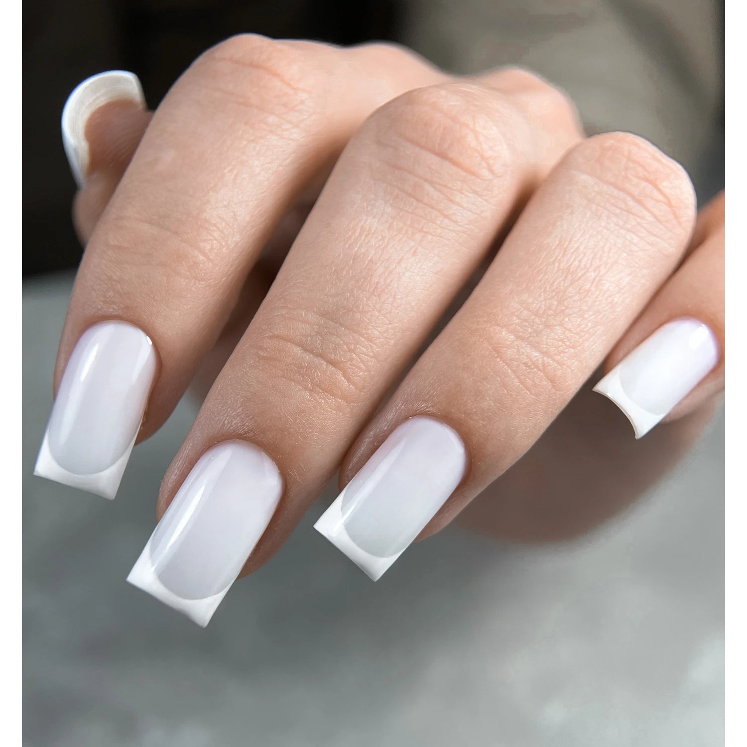 Hand with glossy white square-shaped gel nails, professional manicure
