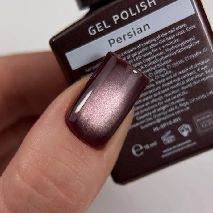Close-up of a fingernail with glossy gradient burgundy gel polish in front of a Persian gel polish bottle