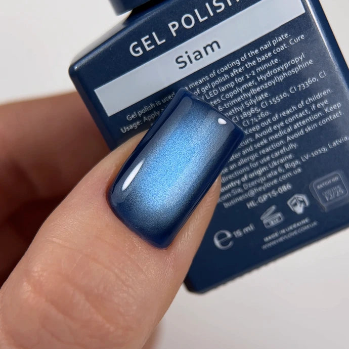 Blue cat eye gel polish on fingernail with Siam gel polish bottle in background