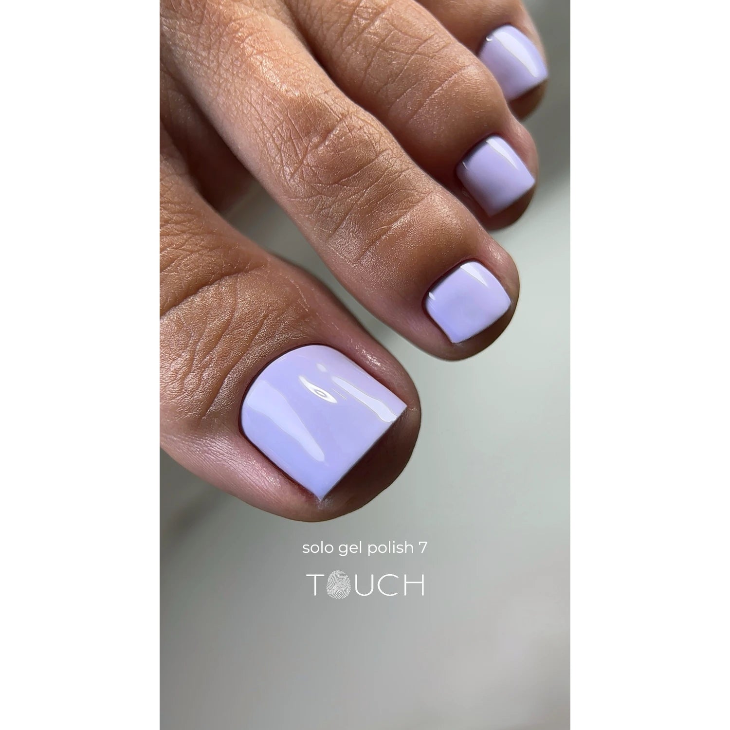 Close-up of toenails painted with glossy pastel purple gel polish, pedicure product display