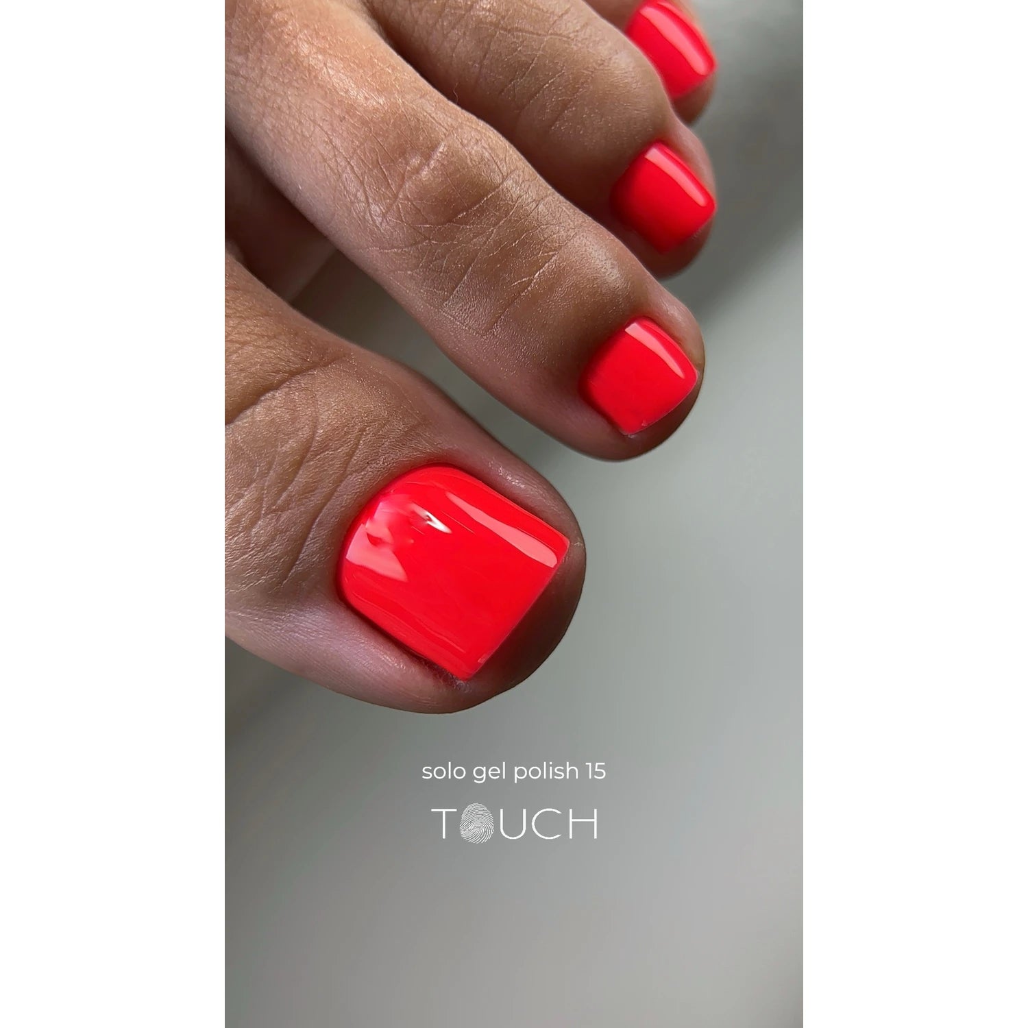 Close-up of toenails with glossy bright coral gel polish pedicure, labeled solo gel polish 15
