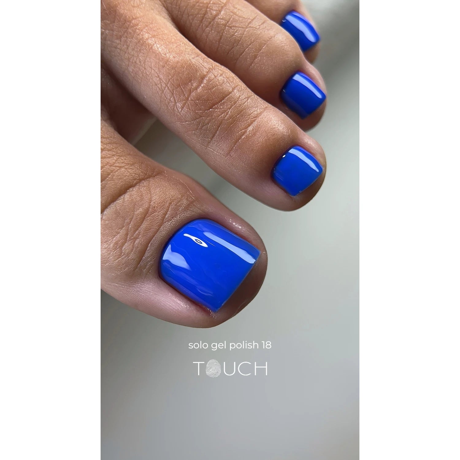 Close-up of toenails painted with glossy blue gel nail polish, professional pedicure