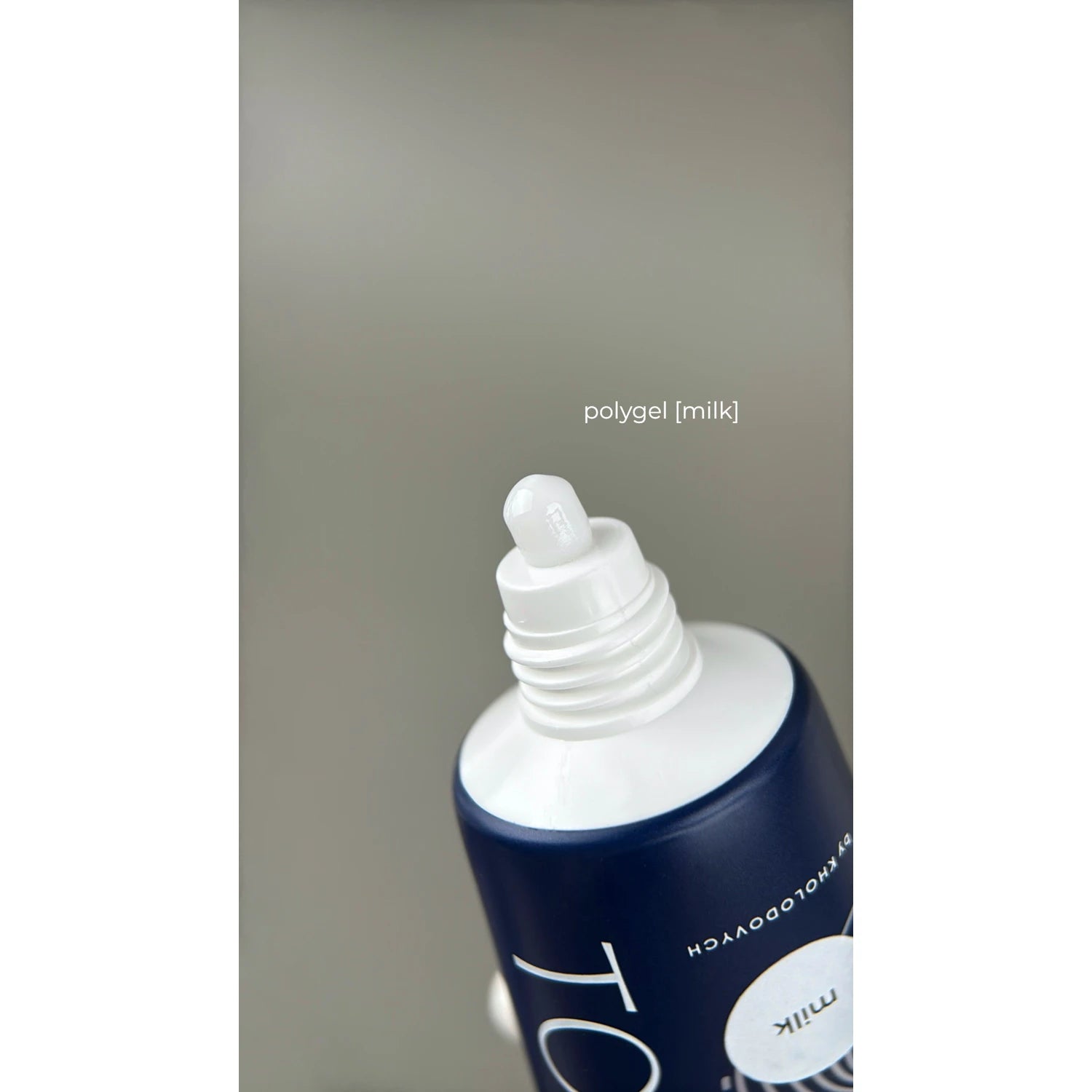 Open tube of milky white polygel for nail extensions against neutral background