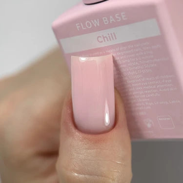 Hand with glossy light pink gel nail polish holding a pink bottle labeled Flow Base Chill.
