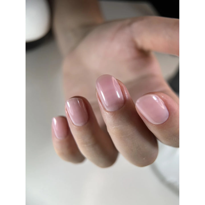 Hand with short, oval-shaped nails featuring glossy light pink UV gel manicure