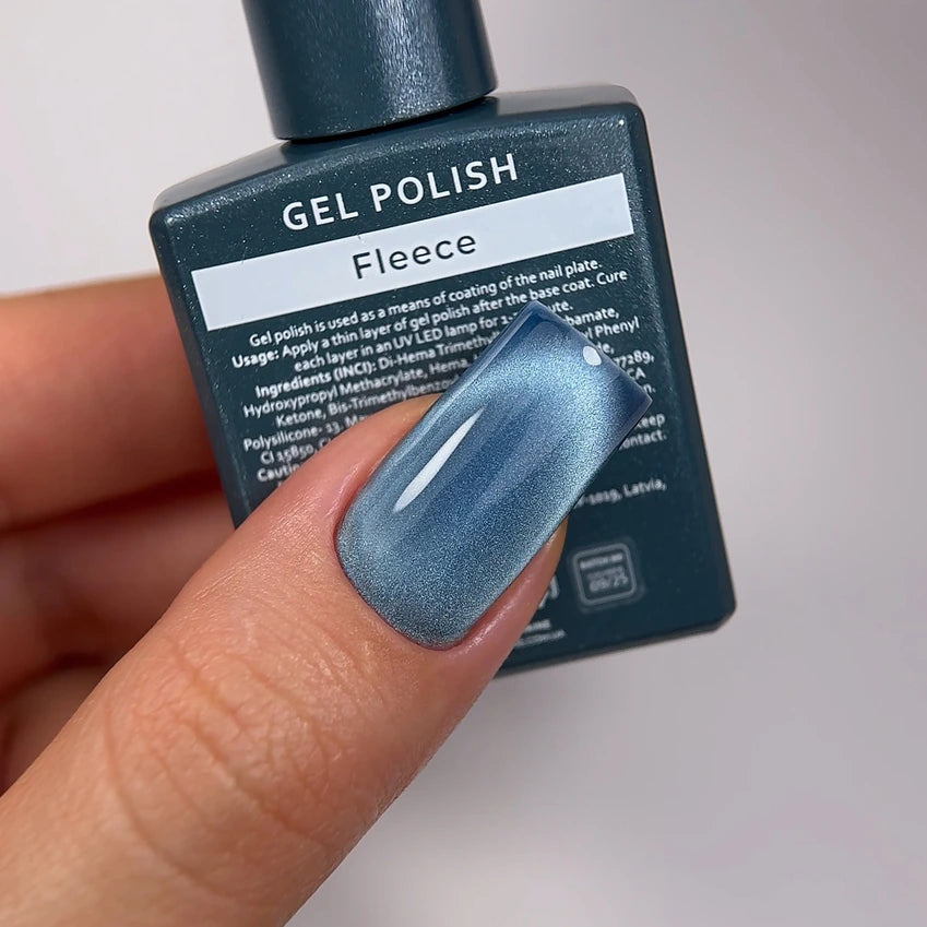 Hand with metallic blue gel polish manicure holding Fleece gel polish bottle