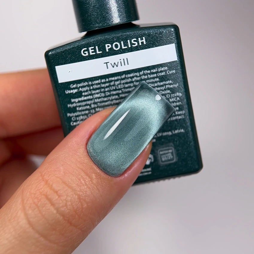 Hand with metallic green gel polish manicure holding Twill gel polish bottle