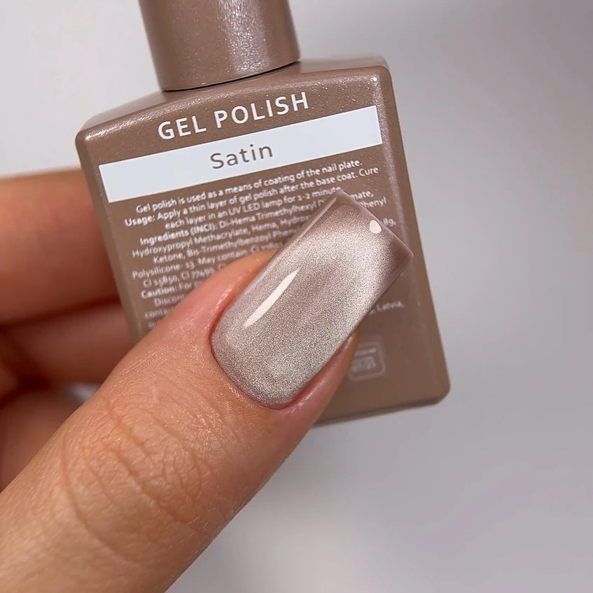 Hand with manicured nail painted in satin beige gel polish, holding gel polish bottle.