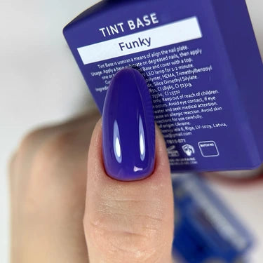 Hand with glossy purple gel polish manicure holding a box labeled 'Tint Base Funky'.