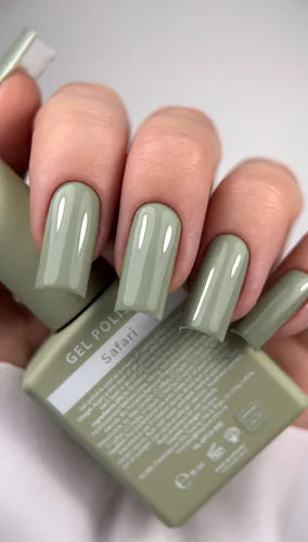 Hand with glossy sage green gel polish manicure, holding matching nail polish bottle