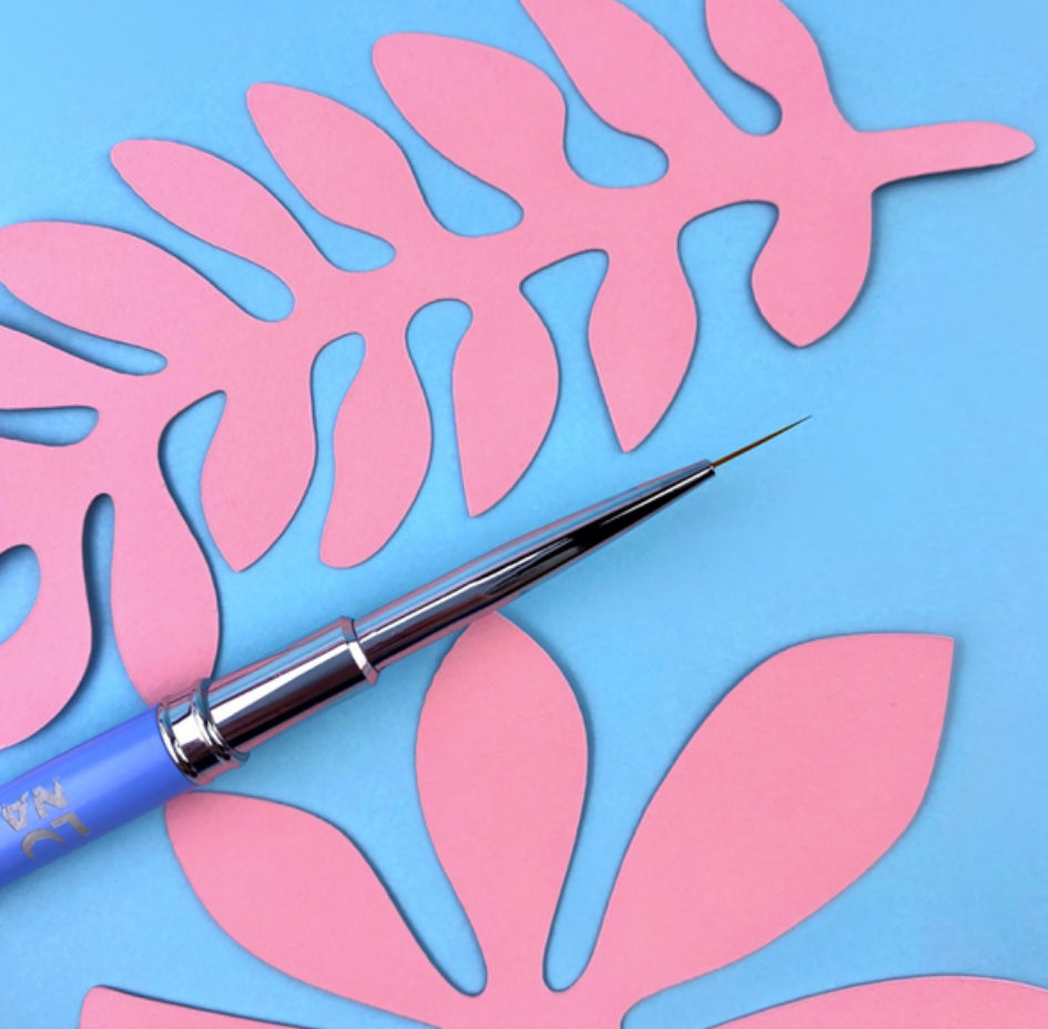 Fine nail art brush with blue handle on pastel paper leaf background for manicure design