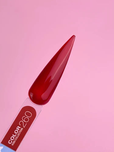 Red nail polish color sample on swatch stick against pink background