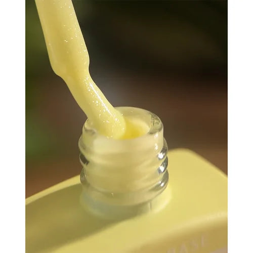Yellow nail polish gel being applied with brush, closeup of bottle and creamy texture