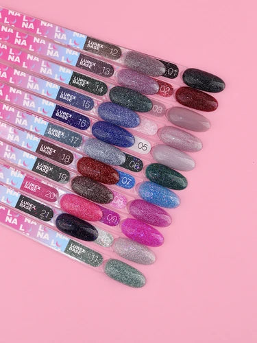 Assorted glitter gel nail polish color swatches on display sticks on a pink background