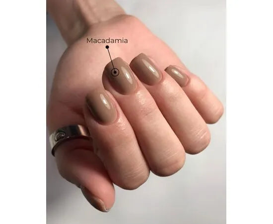 Hand with short, oval nails painted in glossy macadamia beige nail polish