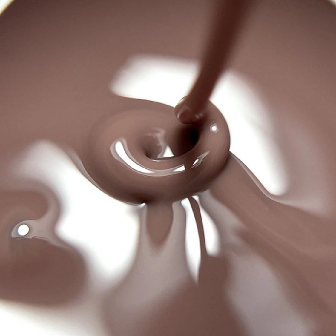 Close-up of glossy brown nail polish gel being poured, perfect for manicures and nail art.