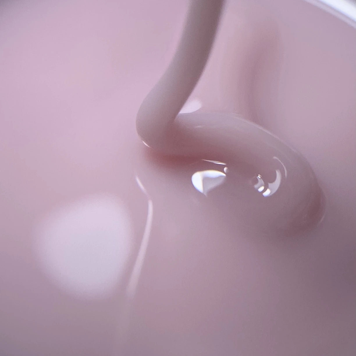 Close-up of pink builder gel for nails, highlighting creamy texture and glossy finish