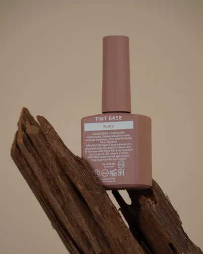 Nude tint base nail polish bottle on a wooden surface, professional manicure product