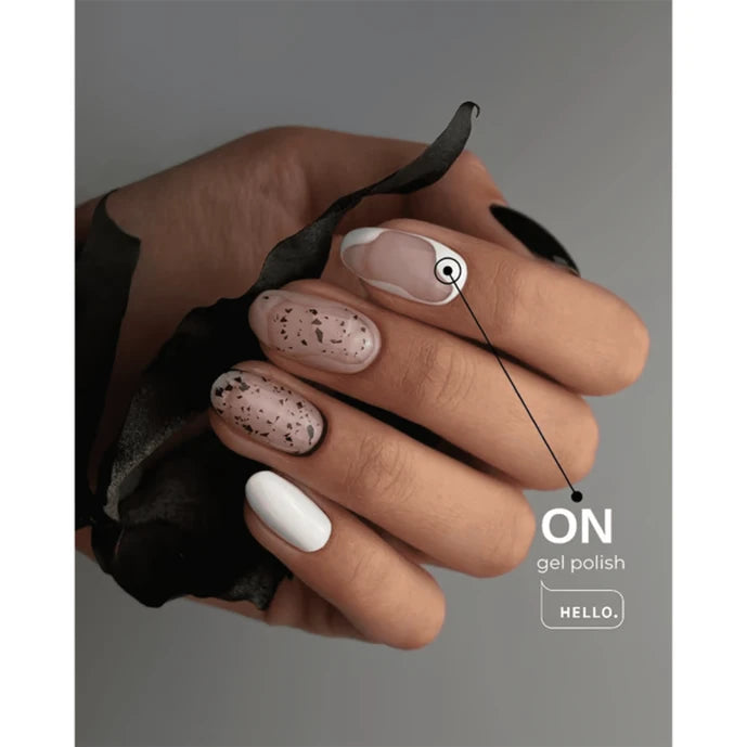 Hand with modern gel manicure featuring white, nude, and black speckled nail designs