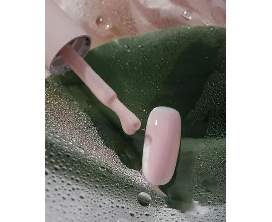 Light peach pink gel nail polish being applied to artificial nail tip, manicure closeup