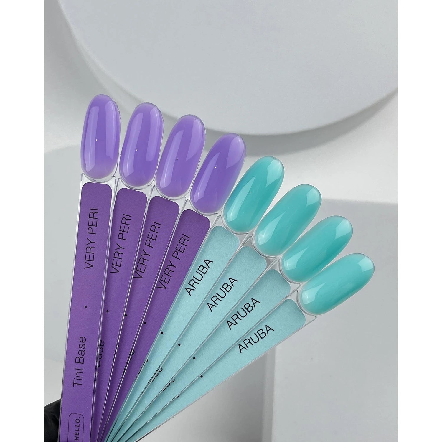 Swatches of purple and teal nail polish samples labeled Very Peri and Aruba for manicure.
